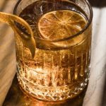 Ice Baths - A glass of whiskey on a table with a slice of lemon