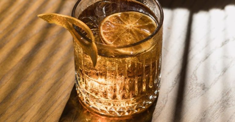 Ice Baths - A glass of whiskey on a table with a slice of lemon
