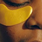 HIIT Routines - Crop gentle African American female with closed eyes and clean face enjoying cosmetic procedure for smoothing and moisturizing skin under eyes and removing dark circles