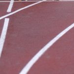 High-Impact Cardio - From above of confident elderly male starting for sprint on racetrack in stadium