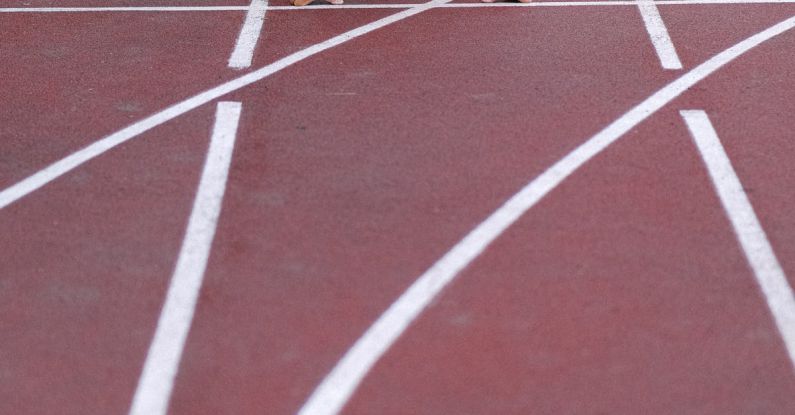 High-Impact Cardio - From above of confident elderly male starting for sprint on racetrack in stadium
