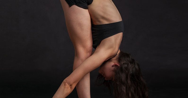 Flexibility - Woman Wearing Black Sports Bra Reaching Floor While Standing