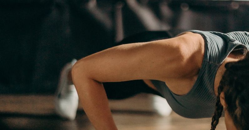 HIIT Workouts - Woman in Black and White Tank Top and Black Shorts Lying on Brown Wooden Floor