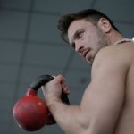 Kettlebell Swings - Strong confident sportsman during training with kettlebell in gym